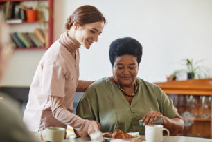 a female caregiver serving an elderly woman