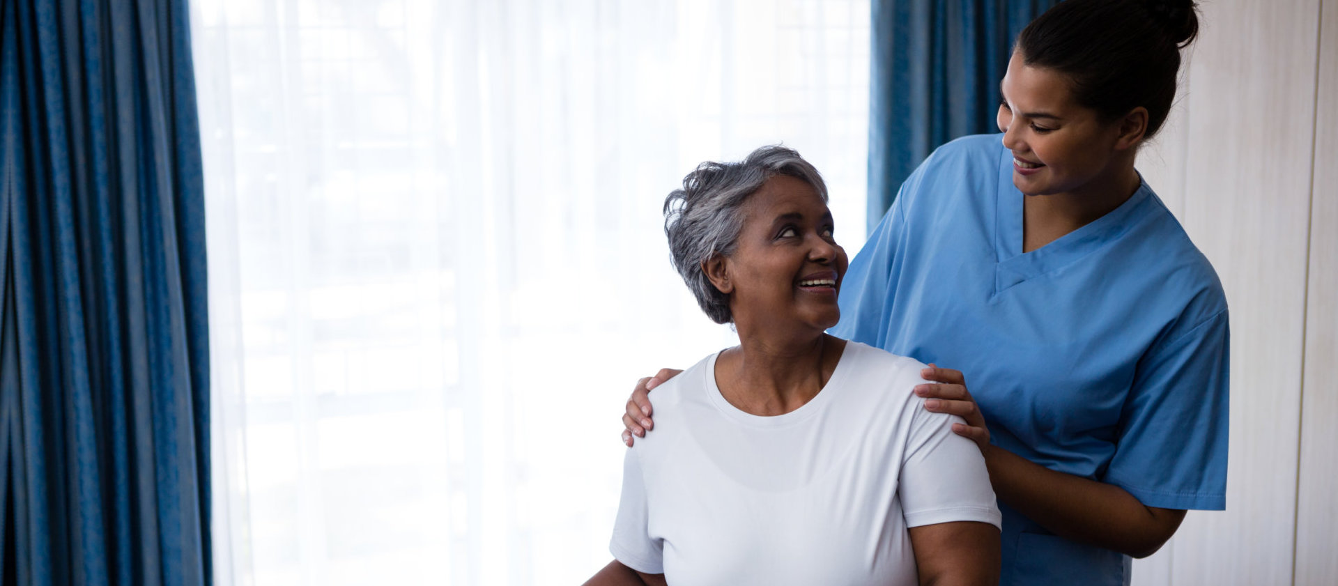 a female caregiver with an elderly woman smiling